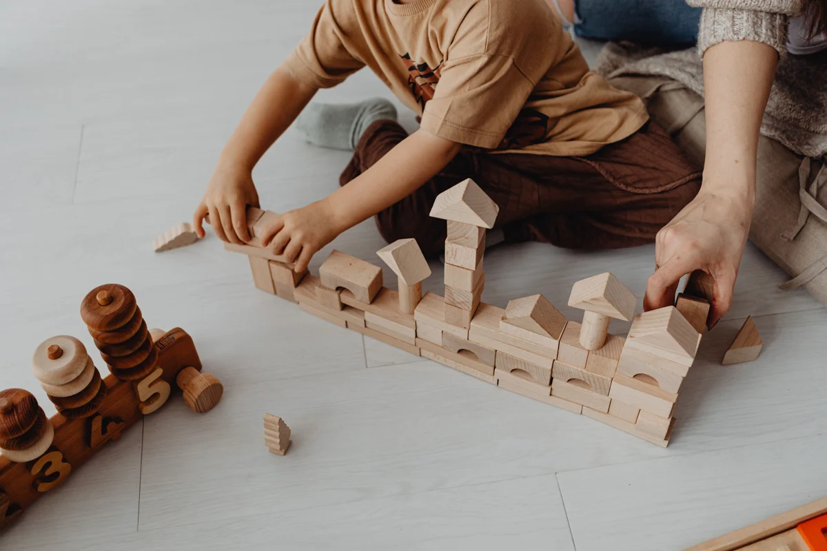 A child and adult building together with wooden blocks.